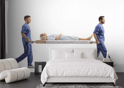 Full length profile shot of healthcare workers carrying a female patient on a stretcher Wall mural