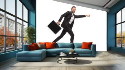 Handsome man in a black suit running with a briefcase and pointing forward Wall mural