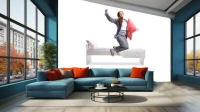 Happy female in pajamas holding a pillow and jumping out of bed Wall mural