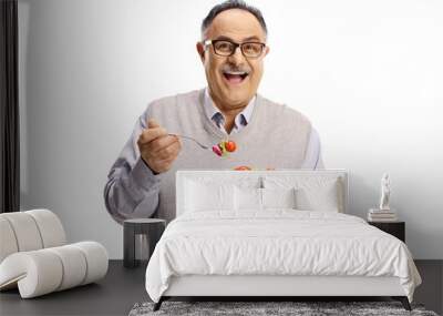 Happy mature man standing and eating a salad Wall mural