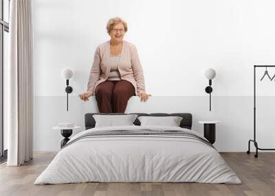 Joyful mature woman sitting on a panel Wall mural