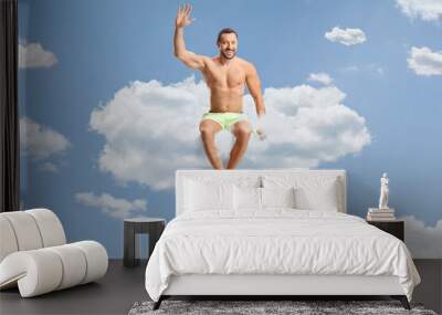 Man in swimwear sitting on a cloud up in the sky Wall mural