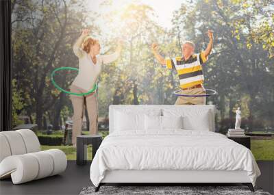 Mature couple exercising with hula hoops in park Wall mural