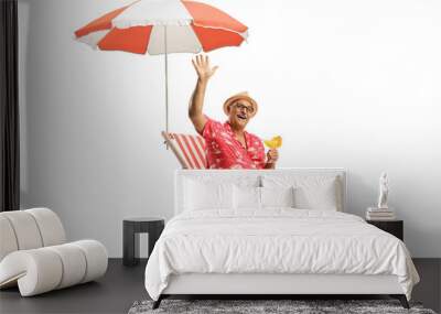 Mature male tourist sitting with a cocktail under umbrella and waving Wall mural