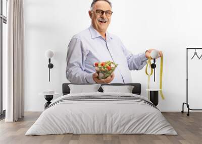 Mature man holding a salad and a measuring tape Wall mural