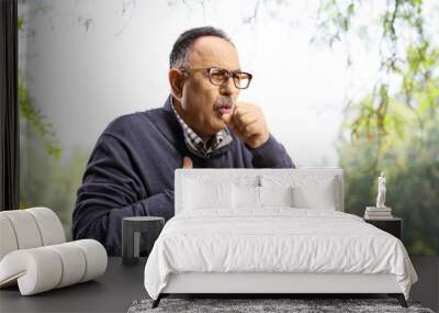 Mature man in a park caughing and holding his chest Wall mural