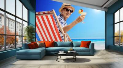 Mature man sitting in a deck chair on a beach Wall mural