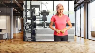 Mature woman at a gym with measuring tape around waist Wall mural