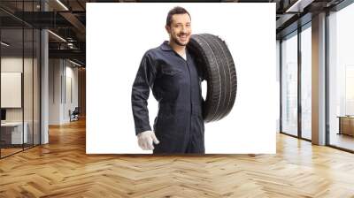 Mechanic holding a car tire and smiling at the camera Wall mural