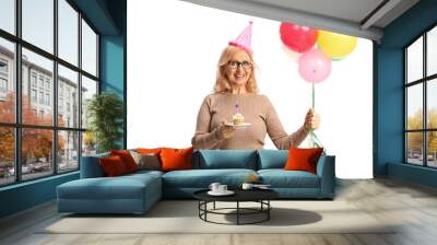 Middle aged woman holding a birthday cupcake and balloons Wall mural