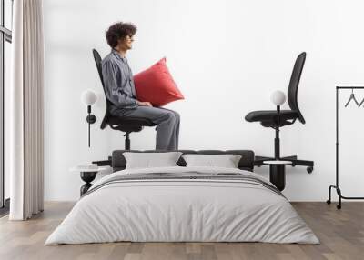 Profile shot of a man in pajamas sitting and looking at an empty office chair Wall mural