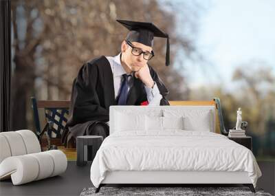 Sad college student sitting on a bench in park Wall mural