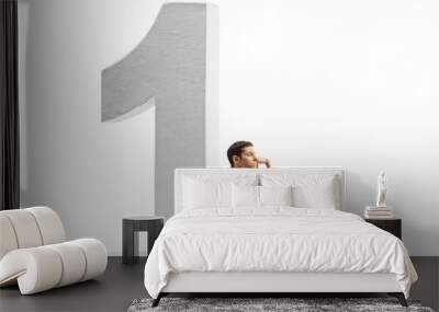 Sad young man in casual clothes sitting on the floor and leaning on a big number one Wall mural