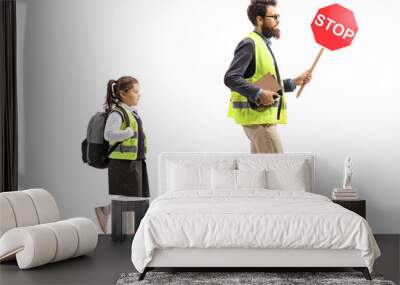 Schoolgirl walking in a safety vest and a man holding a stop traffic sign Wall mural