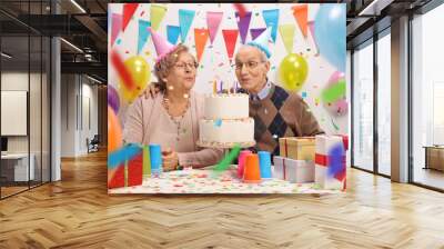 Senior couple blowing candles on a birthday cake Wall mural