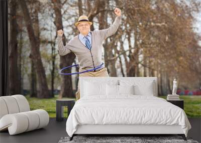 Senior man, exercise with a hula hoop in park Wall mural