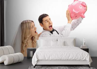 Shocked newlywed couple shaking an empty piggybank Wall mural