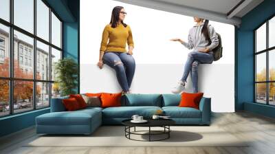 Two young female friends sitting on a panel and talking Wall mural