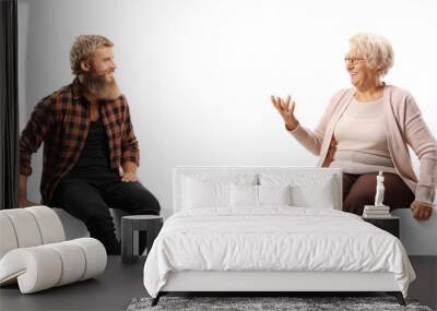 Young bearded man sitting on a white panel board and talking with an older woman Wall mural