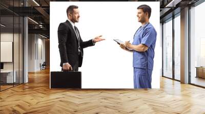 Young businessman with a briefcase gesturing with hand and talking to a doctor in a blue uniform Wall mural