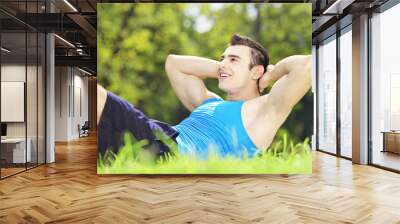 Young male athlete exercising in a park on a grass Wall mural