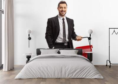 Young man in a suit standing with an empty shopping basket Wall mural