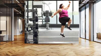 Young overweight woman exercising in a gym Wall mural