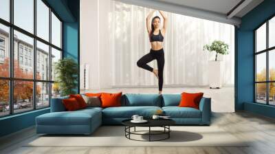 Young woman making a balancing yoga pose at home Wall mural