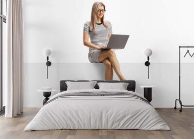 Young woman working on a laptop and sitting on a blank panel Wall mural