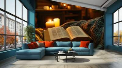 An open book illuminated by candlelight, knit sweater draped over the chair, warm glow, peaceful ambiance, rustic comfort Wall mural