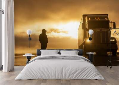 Silhouette of a truck driver standing beside a large semi-truck early morning light fog rolling in open road in the background cool tones strong contrast between the dark figure and the soft light Wall mural