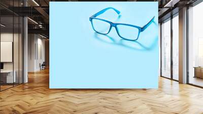 Blue square glasses on blue background with copy space for text. Colorful eyeglasses. Wall mural