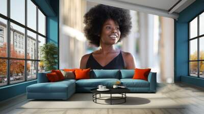 Portrait of smiling young black woman with sunlight flare and copy space Wall mural