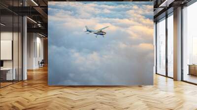 Small single engine airplane flying in the gorgeous sunset sky through the sea of clouds Wall mural