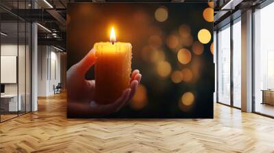 Burning candle in hand on bokeh background  Wall mural