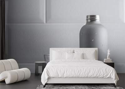 Metal bottle and glass of water on grey textured countertop on a white tile wall background. Water consumption. Wall mural