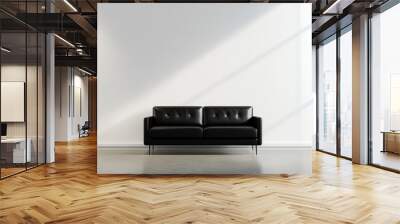 A black leather sofa sits in a minimalist room with a white wall and a concrete floor. The sunlight streams in from a window creating a shadow on the wall. Wall mural