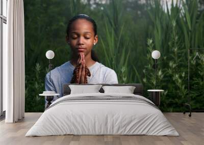 Teenage girl praying outdoors at twilight. Shallow DOF. Wall mural