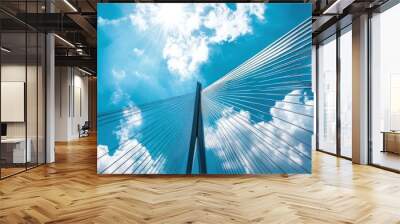 A low angle view of a bridge with a blue sky and white clouds. Wall mural