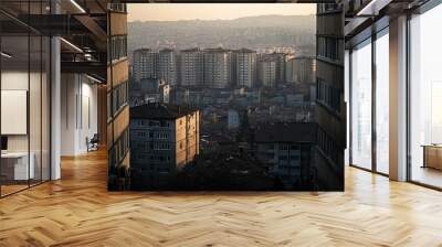 A view of a city from between two buildings with a golden sunset in the background. Wall mural