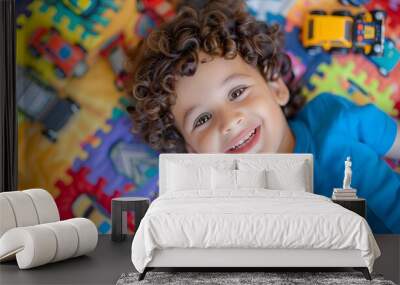 Curly-haired boy playing with colorful toy cars on a vibrant playmat Wall mural