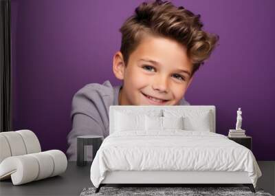 Cute little boy smiling and looking at camera over purple background. Wall mural