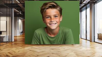 Portrait of a smiling boy in a green t-shirt against a green background Wall mural