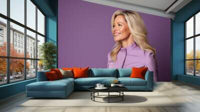 Portrait of a smiling businesswoman in a pink suit on a purple background Wall mural