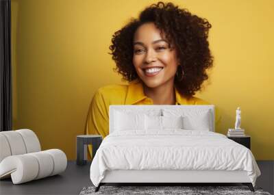 Smiling african american woman in yellow jacket on yellow background Wall mural