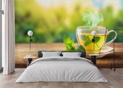 Glass cup of aromatic green tea with fresh mint on wooden table with blurred background Wall mural