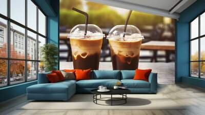 Plastic takeaway cups of delicious iced coffee on table in outdoor cafe with blurry background Wall mural