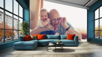 Grandfather playing with baby at table Wall mural