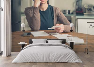 Woman looking at receipts at home Wall mural