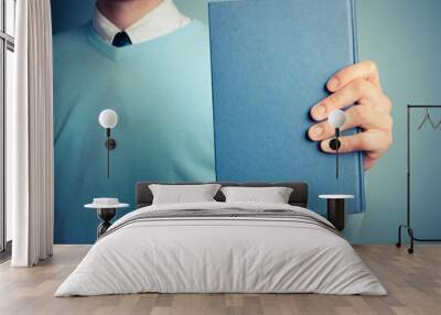 Young man holding a big book Wall mural